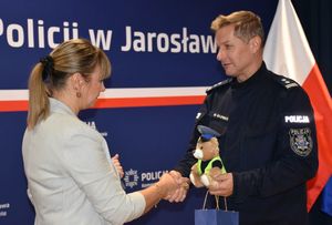 Zastępca Komendanta przekazuje kobiecie maskotkę