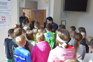 Dzieci z policjantką przy okienku oficera dyżurnego