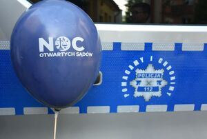 Balon z napisem Noc Otwartych Sądów. W tle policyjny radiowóz