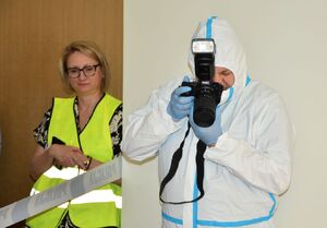 Technik kryminalistyki robi zdjęcie, Obok niego znajduje się kobieta