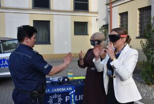 Policjantka z kobietami na policyjnym stoisku. Kobiety mają założone alkogogle i narkogogle