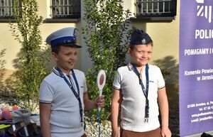 Dwóch chłopców na policyjnym stoisku w policyjnych czapkach