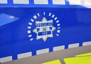 Policyjna gwiazda z napisem pomagamy i chronimy na drzwiach radiowozu