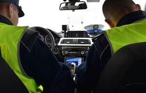 Policjanci w radiowozie wykonują czynności służbowe