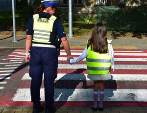 Policjant z dziewczynką na przejściu dla pieszych