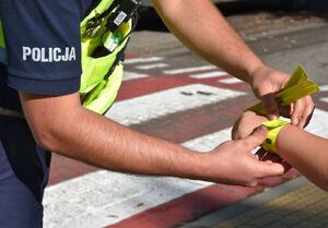 Policjant zakłada odblask dziecku