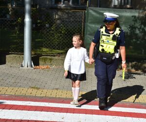 Policjantka przeprowadza dziewczynkę przez przejście dla pieszych