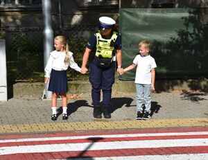 Policjantka przeprowadza chłopca i dziewczynkę przez przejście dla pieszych