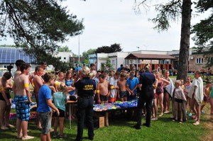 Policjantka i strażniczka miejska mówiąca do dzieci zebranych przy gadżetach na basenie w Jaśle