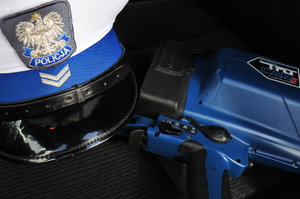 Biała czapka policjanta ruchu drogowego oraz ręczny miernik prędkości na siedzeniu radiowozu