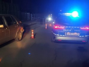 Miejsce zdarzenia drogowego. Z lewej strony uczestniczący pojazd, z prawej radiowóz. W tle policjanci w kamizelkach.