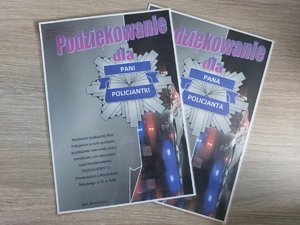 Dwa wydrukowane podziękowania dla policjanta i policjantki. Na kartkach znajduję się napis podziękowanie oraz policyjna gwiazda oraz radiowóz