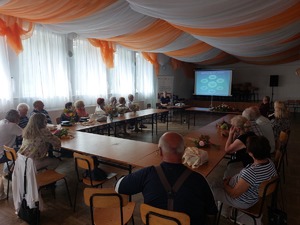 Policjantka mówiąca do siedzących przy stołach seniorów