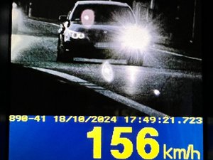 Ekran ręcznego miernika prędkości z wynikiem 156 km/h i wizerunkiem samochodu