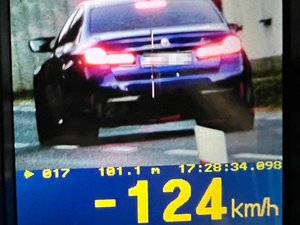 Ekran ręcznego miernika prędkości z wynikiem 124 km/h i wizerunkiem samochodu