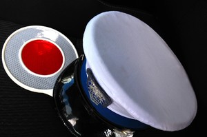 Biała policyjna czapka i tarcza do zatrzymywania pojazdów leżące na siedzeniu