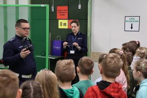 Policjanci pokazujący dzieciom słuchawki ochronne