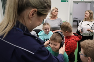 Policjantka nakładająca chłopcu słuchawki ochronne