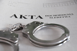 Kajdanki leżące na teczce akt śledztwa/dochodzenia
