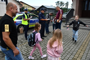Policjanci z wraz z przedstawicielami komisji rozdający ulotki przed szkołami