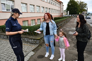 Policjanci z wraz z przedstawicielami komisji rozdający ulotki przed szkołami