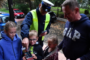 Policjanci z wraz z przedstawicielami komisji rozdający ulotki przed szkołami