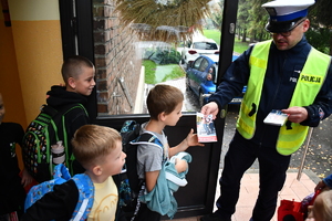 Policjanci z wraz z przedstawicielami komisji rozdający ulotki przed szkołami