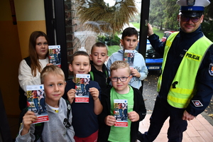 Policjanci z wraz z przedstawicielami komisji rozdający ulotki przed szkołami