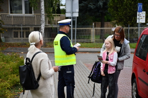 Policjanci z wraz z przedstawicielami komisji rozdający ulotki przed szkołami