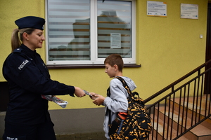 Policjanci z wraz z przedstawicielami komisji rozdający ulotki przed szkołami