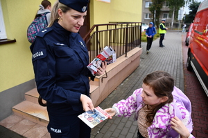Policjanci z wraz z przedstawicielami komisji rozdający ulotki przed szkołami