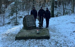 policjanci palą znicz w miejscu katastrofy