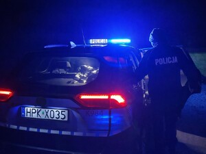 policjanci w nocy pomagają leżącemu na jezdni mężczyźnie