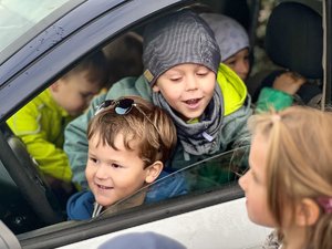 Zdjęcie przedstawia grupę dzieci znajdujących się w samochodzie służbowym. Zdjęcie wykadrowane na twarz dzieci.