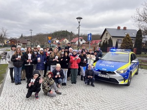 Na zdjęciu widoczny jest oznakowany radiowóz oraz uczestnicy spotkania z policjantami leżajskiej komendy. Zdjęcie zrobione na zewnątrz.