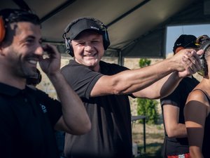 Zdjęcia przedstawiają przebieg otwartych zawodów strzeleckich, połączonych z piknikiem rodzinnym na strzelnicy arizona w Przychojcu. Na zdjęciach widoczni są także policjanci, którzy współorganizowali wydarzenie. Strzelnica zlokalizowana jest wśród wałów ziemnych, które również widoczne są na zdjęciach.