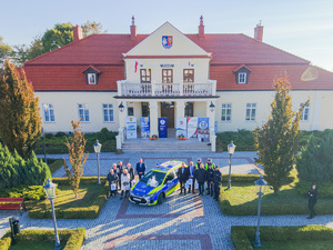 Zdjęcia przedstawiają uroczyste przekazanie nowego radiowozu dla Komendy Powiatowej Policji w Leżajsku. Spotkanie miało miejsce przy Muzeum Ziemi Leżajskiej. W przekazaniu udział wzięli przedstawiciele jednostek samorządu lokalnego. Na zdjęciach znajdują się także umundurowani funkcjonariusze oraz oznakowany radiowóz.