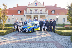 Zdjęcia przedstawiają uroczyste przekazanie nowego radiowozu dla Komendy Powiatowej Policji w Leżajsku. Spotkanie miało miejsce przy Muzeum Ziemi Leżajskiej. W przekazaniu udział wzięli przedstawiciele jednostek samorządu lokalnego. Na zdjęciach znajdują się także umundurowani funkcjonariusze oraz oznakowany radiowóz.