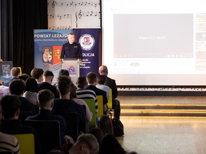 Zdjęcia przedstawiają przebieg debaty. Na zdjęciach widoczni są umundurowani policjanci oraz prelegenci. Debata społeczna odbyła się w Zespole Szkół Licealnych im. Bolesława Chrobrego. Na wybranych kadrach widoczna jest tłumnie zgromadzona na sali koncertowej młodzież.
