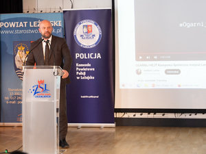 Zdjęcia przedstawiają przebieg debaty. Na zdjęciach widoczni są umundurowani policjanci oraz prelegenci. Debata społeczna odbyła się w Zespole Szkół Licealnych im. Bolesława Chrobrego. Na wybranych kadrach widoczna jest tłumnie zgromadzona na sali koncertowej młodzież.