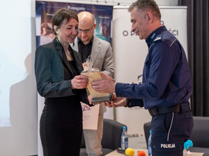 Zdjęcia przedstawiają przebieg debaty. Na zdjęciach widoczni są umundurowani policjanci oraz prelegenci. Debata społeczna odbyła się w Zespole Szkół Licealnych im. Bolesława Chrobrego. Na wybranych kadrach widoczna jest tłumnie zgromadzona na sali koncertowej młodzież.