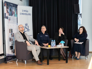 Zdjęcia przedstawiają przebieg debaty. Na zdjęciach widoczni są umundurowani policjanci oraz prelegenci. Debata społeczna odbyła się w Zespole Szkół Licealnych im. Bolesława Chrobrego. Na wybranych kadrach widoczna jest tłumnie zgromadzona na sali koncertowej młodzież.