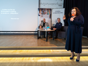 Zdjęcia przedstawiają przebieg debaty. Na zdjęciach widoczni są umundurowani policjanci oraz prelegenci. Debata społeczna odbyła się w Zespole Szkół Licealnych im. Bolesława Chrobrego. Na wybranych kadrach widoczna jest tłumnie zgromadzona na sali koncertowej młodzież.