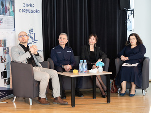 Zdjęcia przedstawiają przebieg debaty. Na zdjęciach widoczni są umundurowani policjanci oraz prelegenci. Debata społeczna odbyła się w Zespole Szkół Licealnych im. Bolesława Chrobrego. Na wybranych kadrach widoczna jest tłumnie zgromadzona na sali koncertowej młodzież.