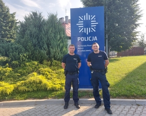 Na zdjęciu przed budynkiem Komendy Powiatowej Policji w Lubaczowie stoi dwóch umundurowanych funkcjonariuszy policji.
