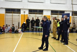 Na sali gimnastycznej uczniowie, policjanci i strażacy.