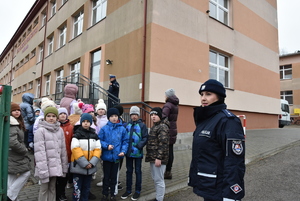 Przed szkoła uczniowie i policjanci.