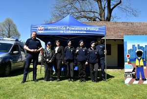 Harcerze z policjantami przy namiocie policyjnym.