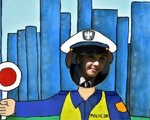 Dziewczynka przy ściance zdjęciowej przedstawiającej  policjanta.