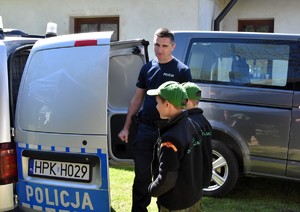 Policjant pokazuje dzieciom radiowóz.